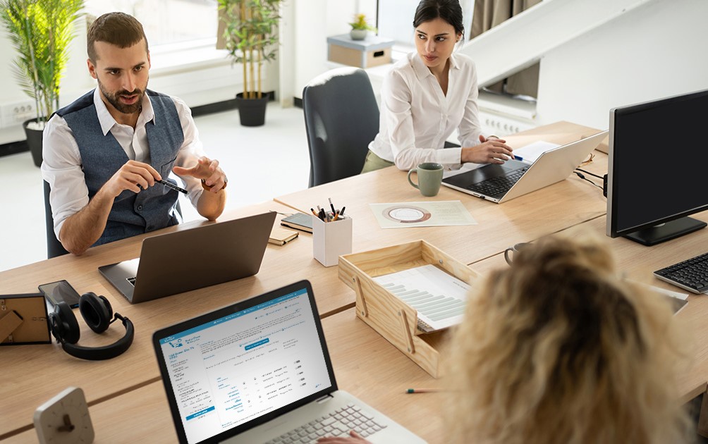 Lender and client holding a laptop and tablet reviewing real estate closing documents.