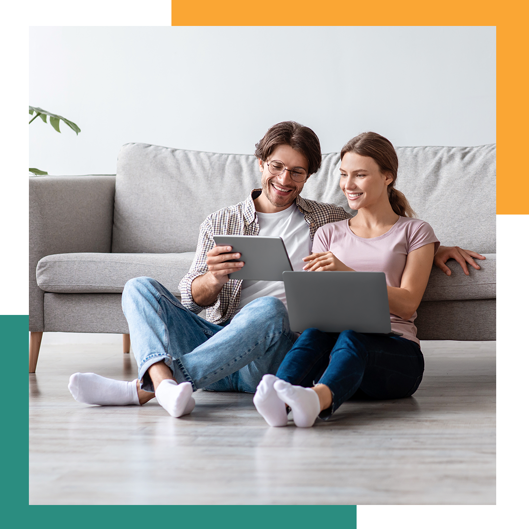 Two people sitting on the ground looking at a tablet.