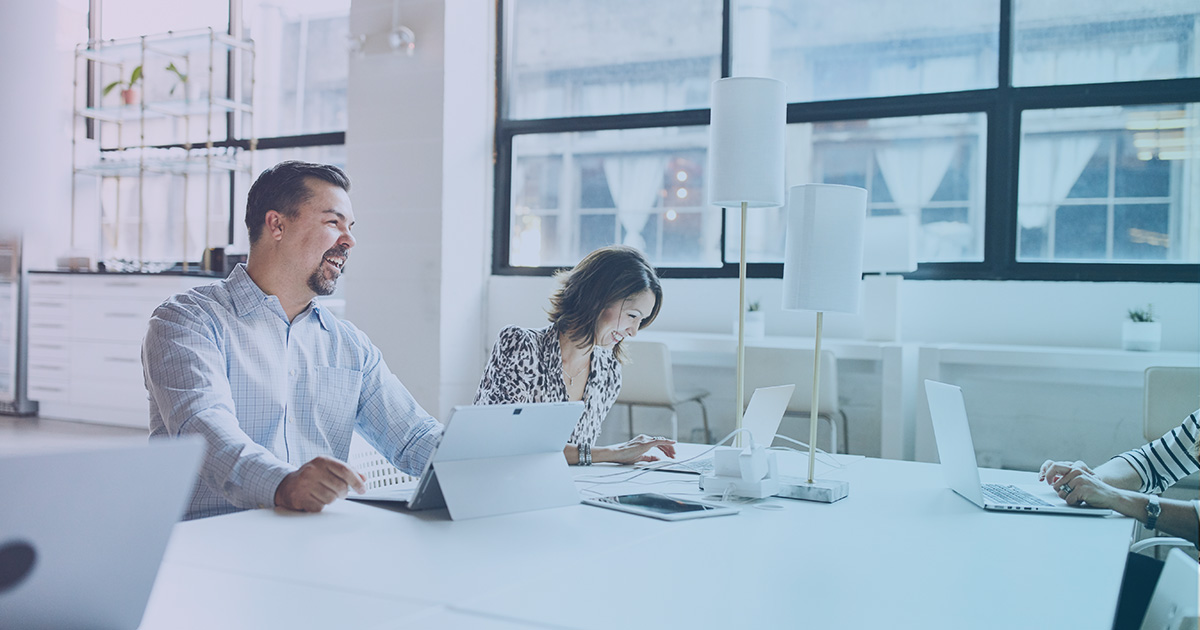 Two people sitting at a table with their tablets.