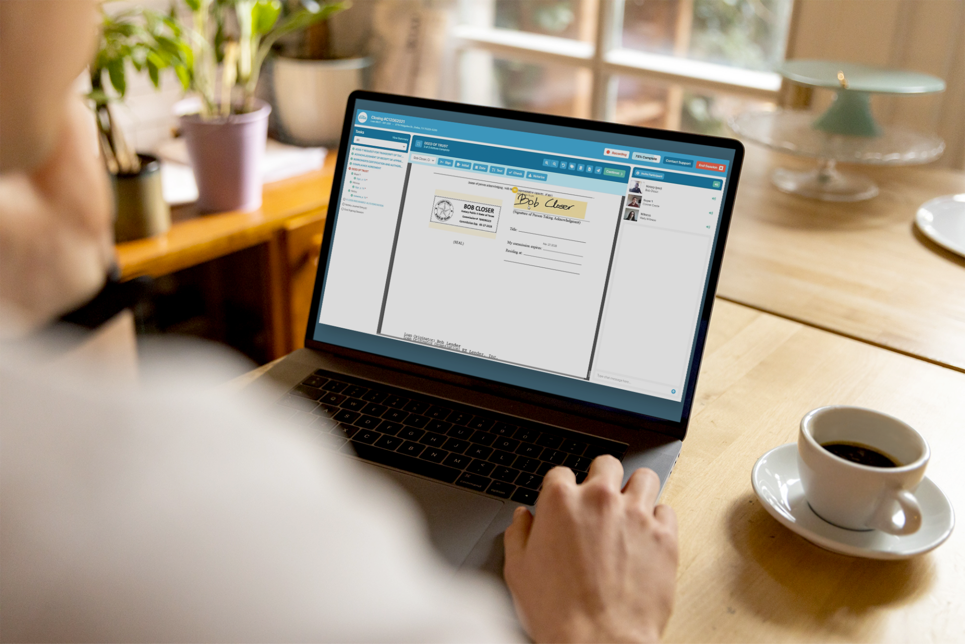 A person on a laptop with a coffee cup next to the laptop on the table.