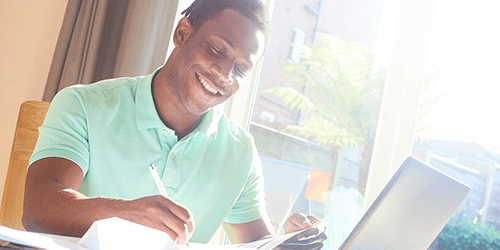 A person smiling looking at their laptop.