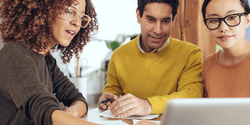 Three people looking at a laptop.