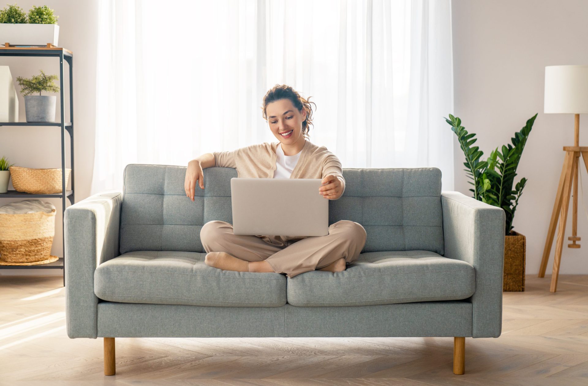 woman sitting cross-legged on couch opening her laptop